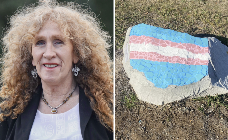 Side by side diptych; on the left a woman with curly blonde hair smiles, wearing a black jacket over a white top, and jewellery including a necklace with a pendant and dragon-shaped earrings. On the right, a rock decorated with a mosaic of the transgender pride flag, featuring stripes of light blue, pink, and white, laid out on the ground.